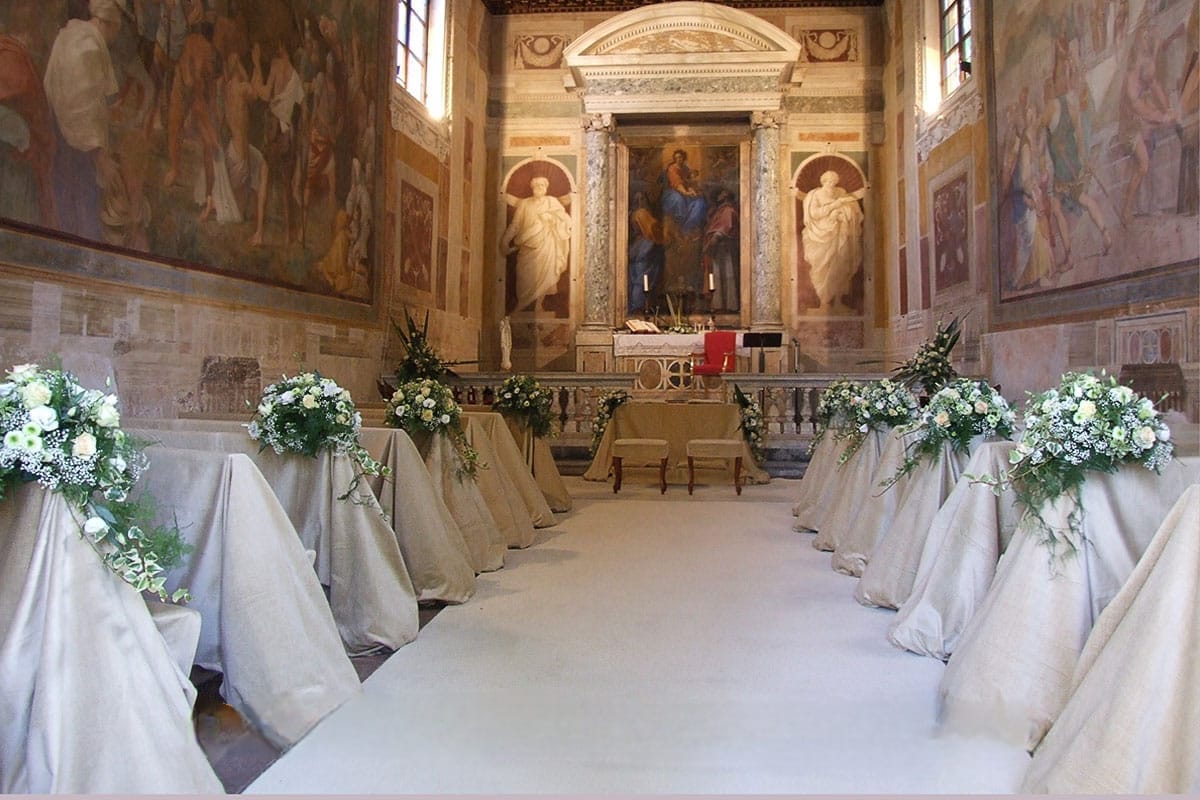 Cerimonia all'aperto con sedute decorate e composizioni floreali