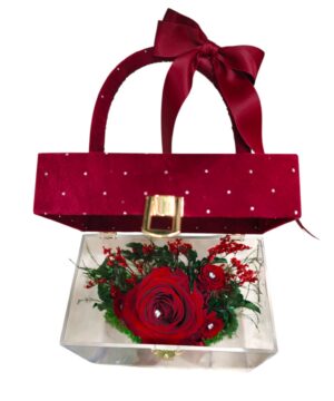 Borsa decorativa rossa chiusa con rose stabilizzate visibili attraverso la parte trasparente